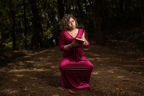Woman in Red Dress Reading Book in Forest
