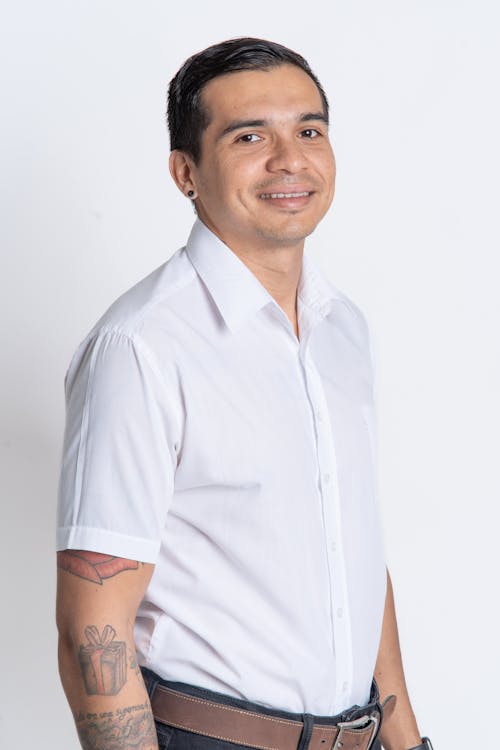 Studio Shot of a Man with Tattoos Wearing a White Shirt and Smiling 