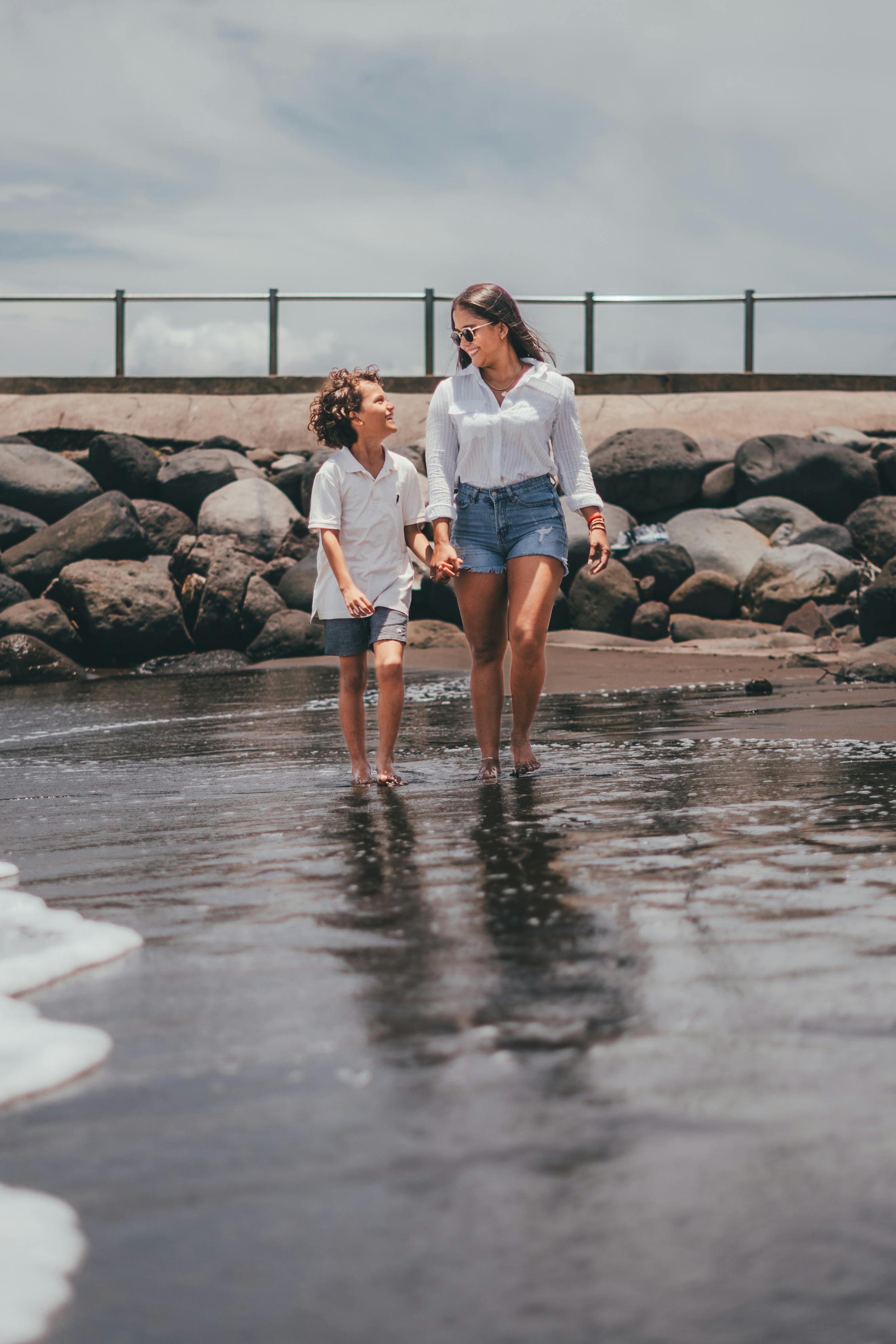 woman with her son walking ankles deep in water and smiling