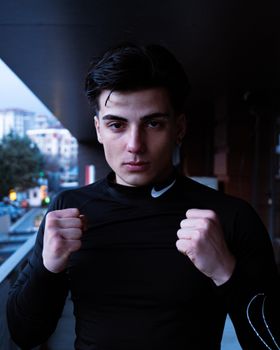 Young man in black athletic shirt displaying confidence in urban outdoor environment.