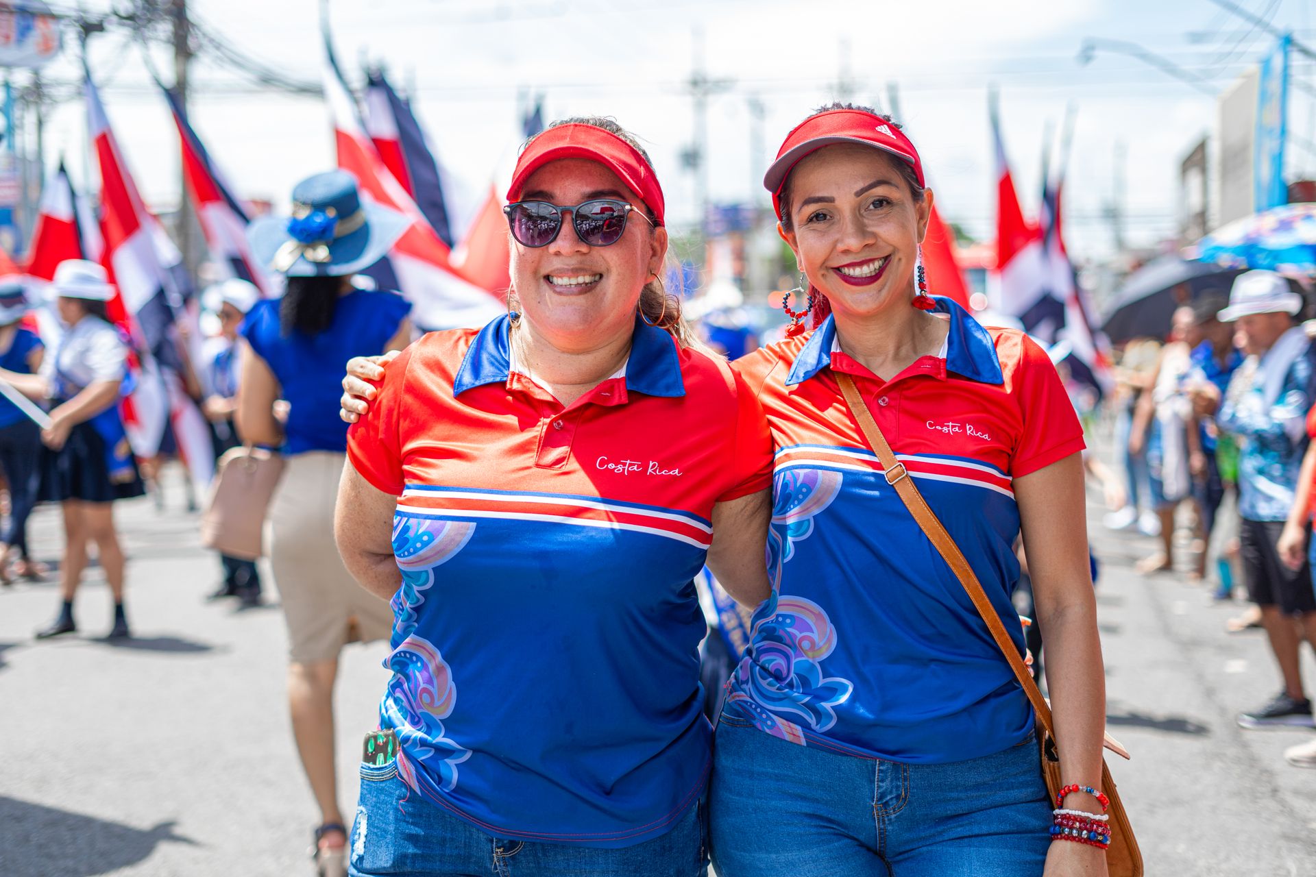 Two women in traditional attire celebrating on the streets of Costa Rica during a vibrant parade.