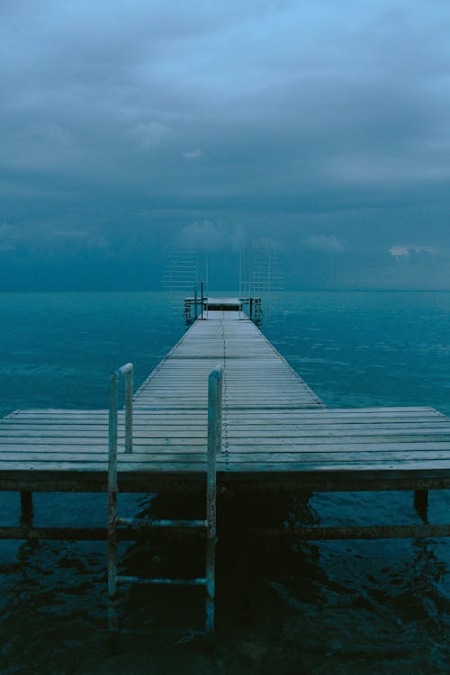 A pier with a cloudy sky and water
