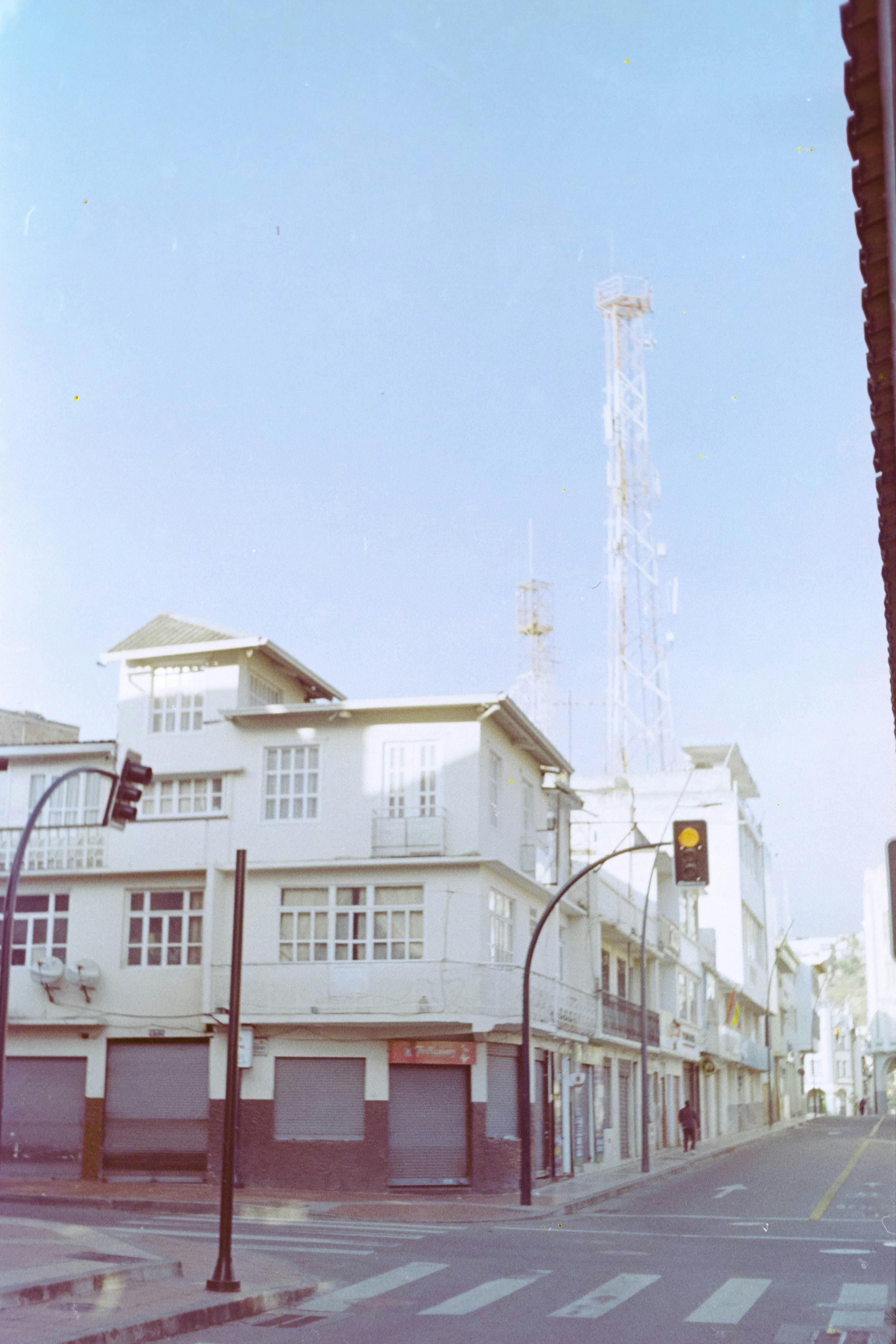 Street view of an urban area with residential buildings and a communication tower on a clear day.