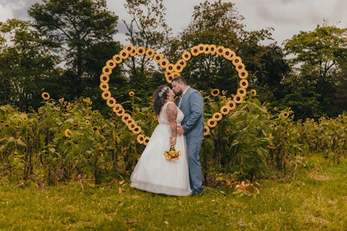 Bride and Groom Standing on a Sunflower Field 