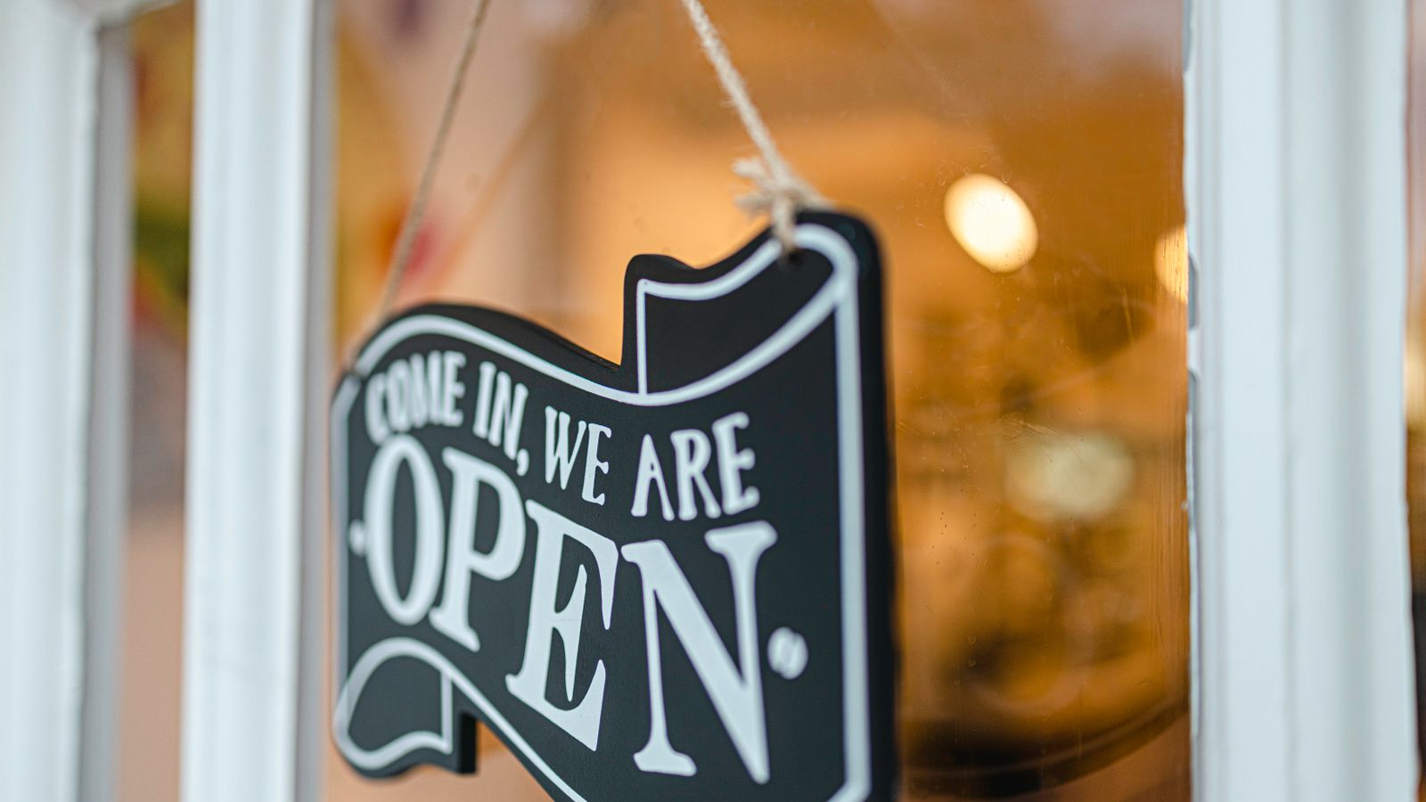 A welcoming open sign hanging on a glass door, inviting customers to enter.