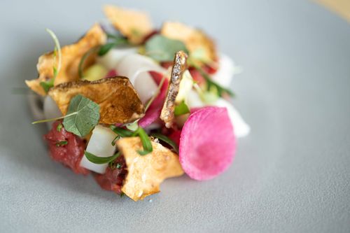 Free Artfully plated gourmet dish with fresh vegetables and crispy garnish on a minimalist plate. Stock Photo