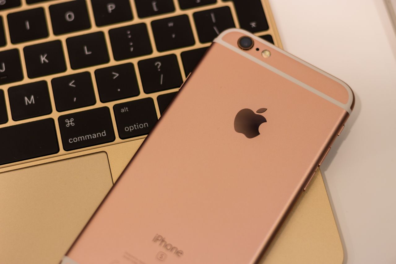 close up of a rose gold iphone 6s placed on a macbook keyboard showcas