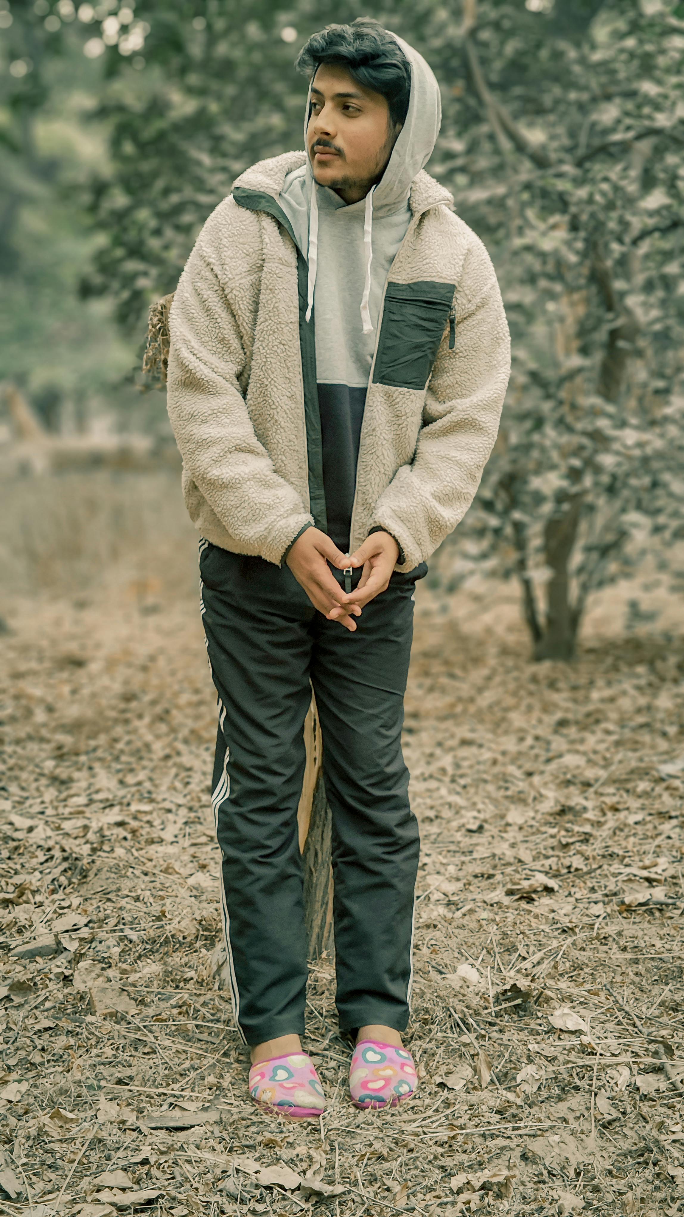 Young man in trendy attire posing in a forest setting. Stylish and relaxed vibe.