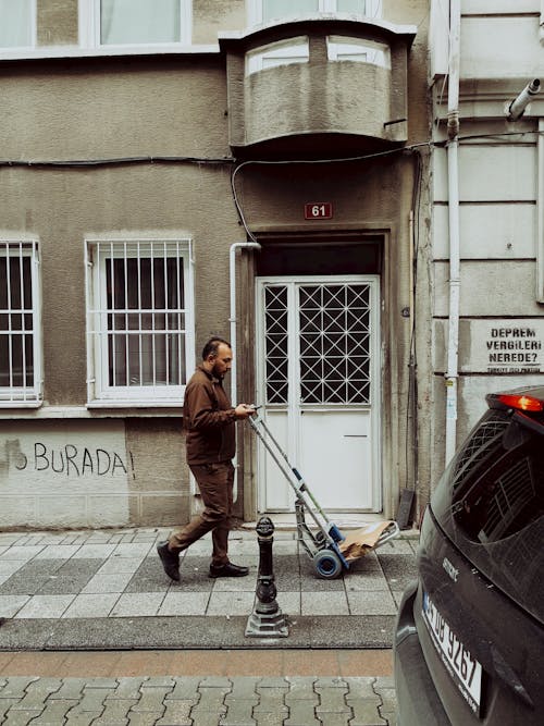 Delivery Man Pushing a Cart Checking Messages on His Phone