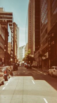 A bustling downtown street lined with tall buildings and parked cars in the daytime.