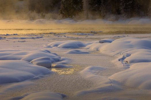 Snow-covered river and trees during a stunning sunset in Sørumsand, Norway.