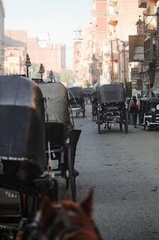 A lively urban street scene in Luxor, Egypt, with horse-drawn carriages lined up.