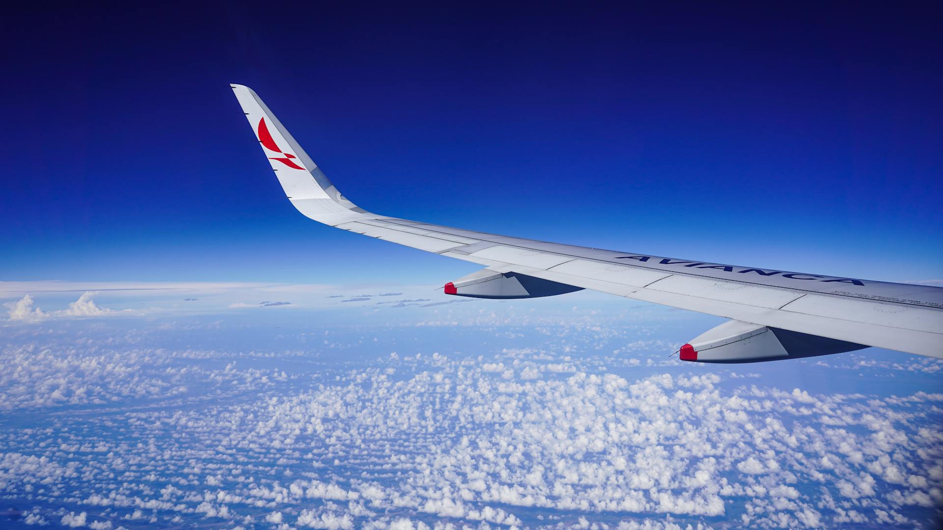 Stunning aerial view of an Avianca airplane wing above clouds during flight over Colombia.