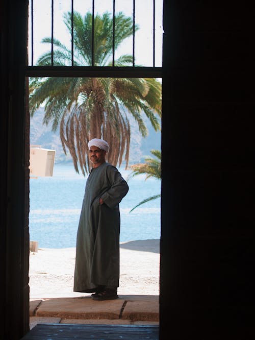 A man in a traditional arabic outfit stands in front of a door