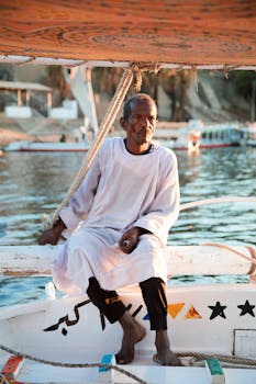 Elderly man sits on a traditional boat by the Nile River in Luxor, Egypt.