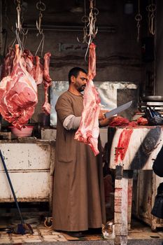An Egyptian butcher skillfully prepares meat at an open-air market stall in Luxor, Egypt.