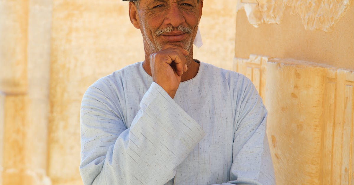 An old man in traditional clothing poses for a photo