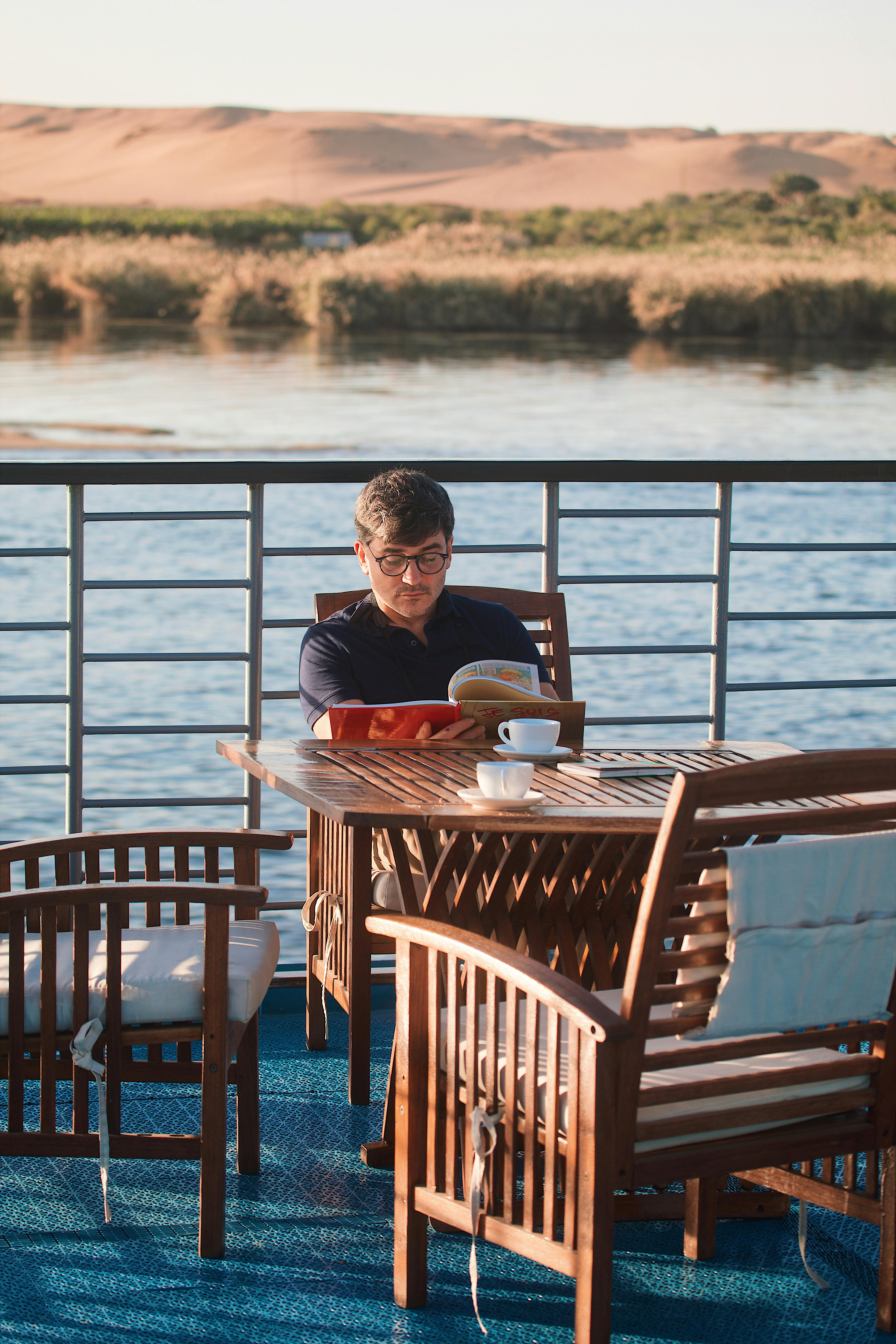 a man reading on a deck overlooking the nile river