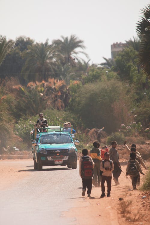 A group of people walking down a road with a car