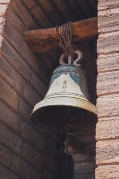 A close-up of a historic metal bell hanging inside a stone tower in Ayacucho, Peru.