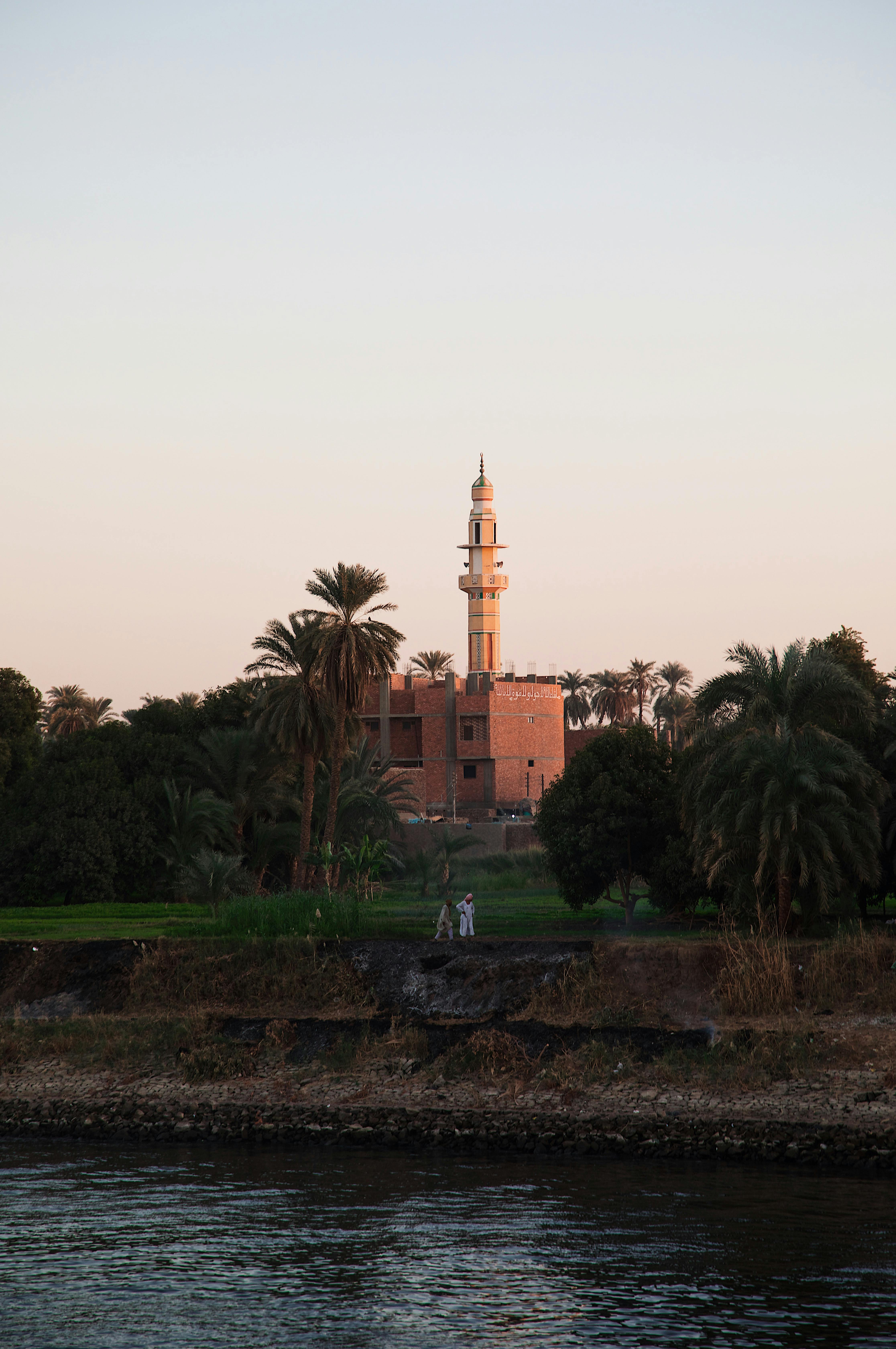 Serene image of a mosque at sunset, reflected on the Nile river, Luxor, Egypt.