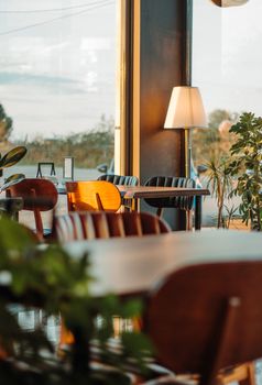 Sunlit cafe interior with wooden chairs, tables, and greenery. Perfect setting for relaxation.
