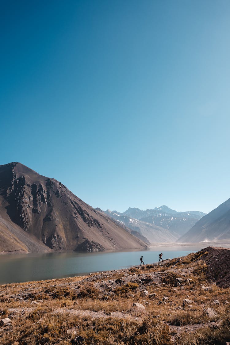 Two People Trekking By The El Yeso Dam