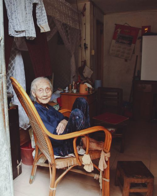 Free An elderly woman sits comfortably in a wooden armchair inside a cozy room, evoking a sense of warmth and tranquility. Stock Photo
