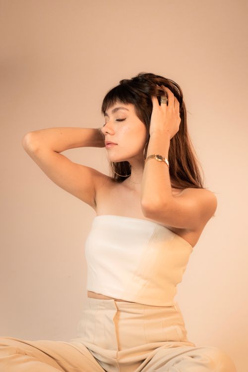 Free A woman in a strapless top poses with eyes closed, exuding modern fashion in a studio setting. Stock Photo