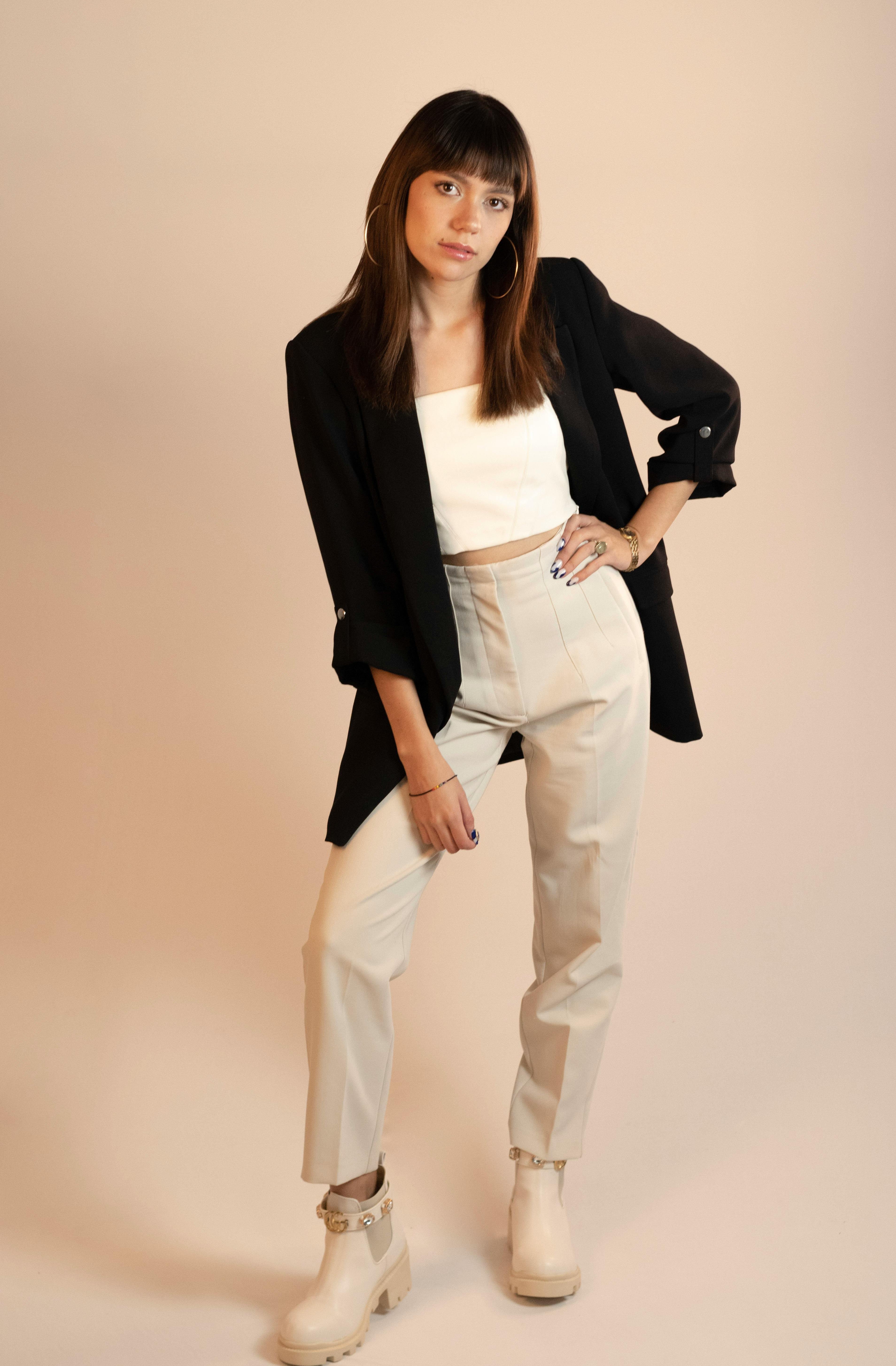 Young woman in modern fashion outfit posing playfully during a studio shoot.