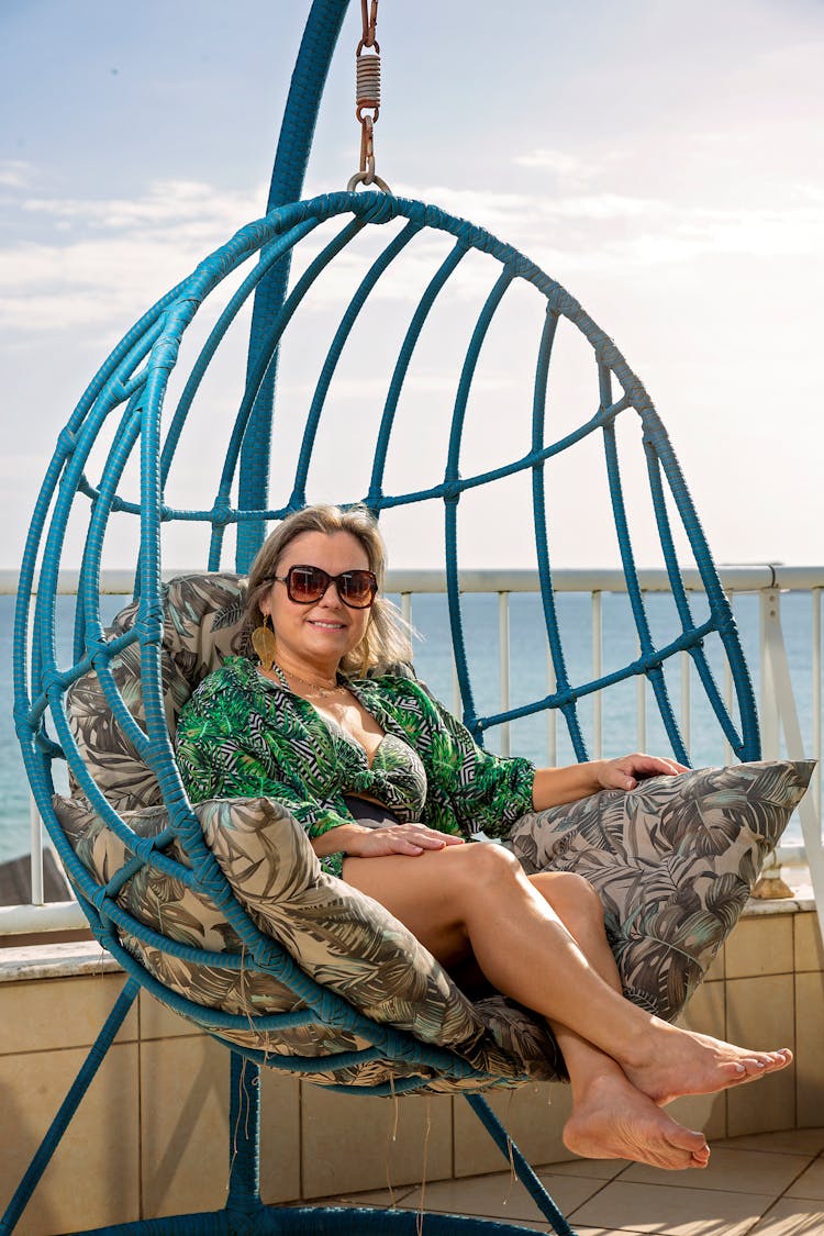 Smiling Woman In Sunglasses Sitting On Egg Chair