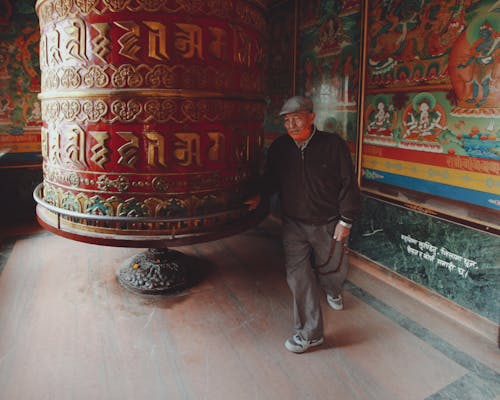 Man near Ornamented Bell at Buddhist Temple
