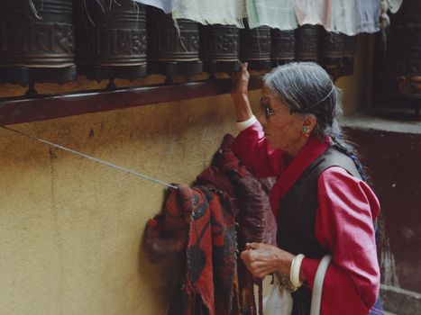 Elderly Woman Standing near Bells at Buddhist Temple