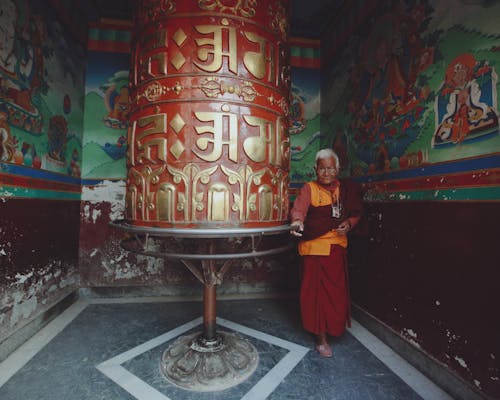 Monk Standing by Ornamented Bell at Buddhist Temple