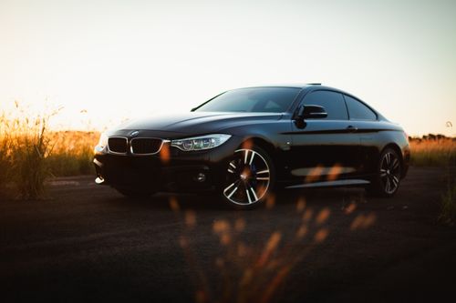 Free A black BMW 4 Series sports car parked on a rural road during sunset, capturing a serene and elegant moment. Stock Photo