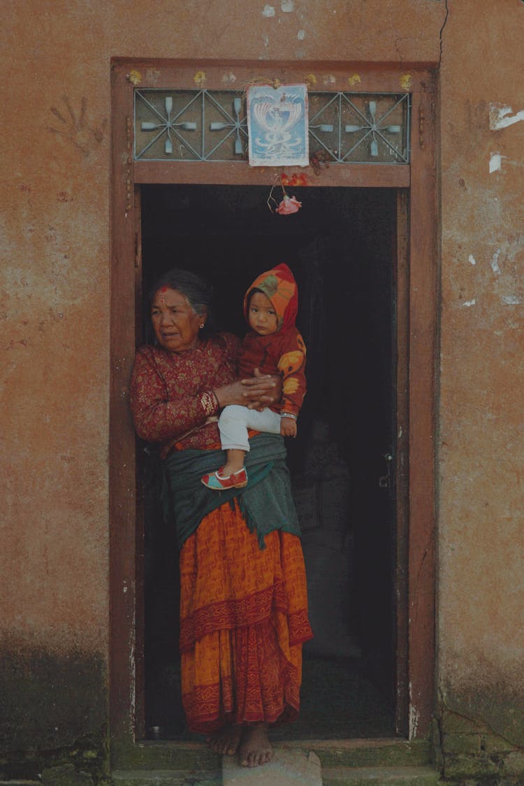 Grandma In Traditional Clothing Standing With Baby