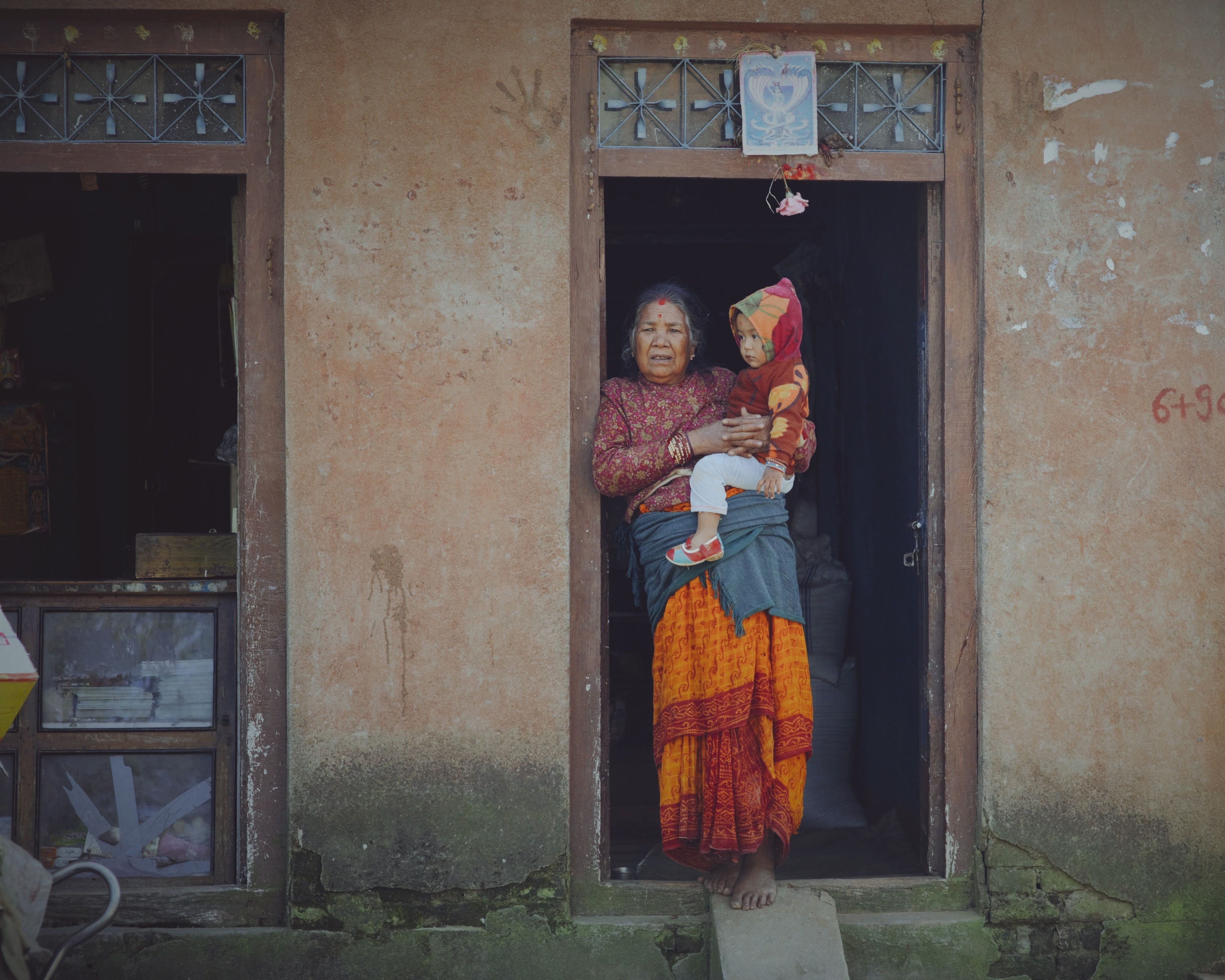 A woman holding a baby in front of a door · Free Stock Photo