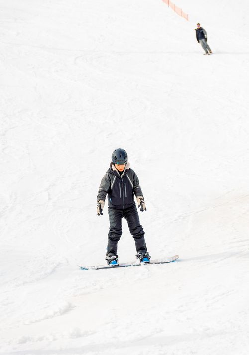 Free Young child snowboarding down snowy slopes in Yuzawa, Niigata, Japan, during winter sports activity. Stock Photo