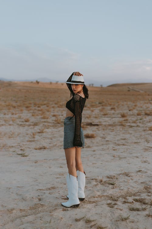 Young Woman in a Fashionable Outfit with Cowboy Boots Posing in the Desert 