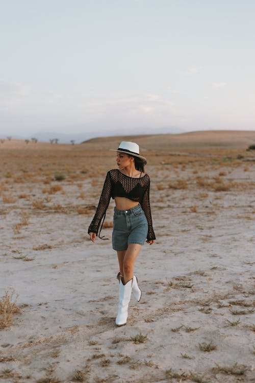 Young Woman in a Fashionable Outfit with Cowboy Boots Posing in the Desert 