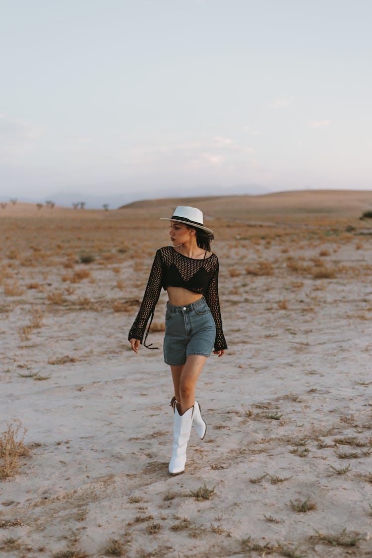 Young Woman In A Fashionable Outfit With Cowboy Boots Posing In The Desert 