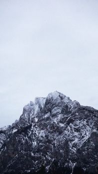 A dramatic snowcapped mountain peak under an overcast sky, highlighting the natural beauty and winter landscape.