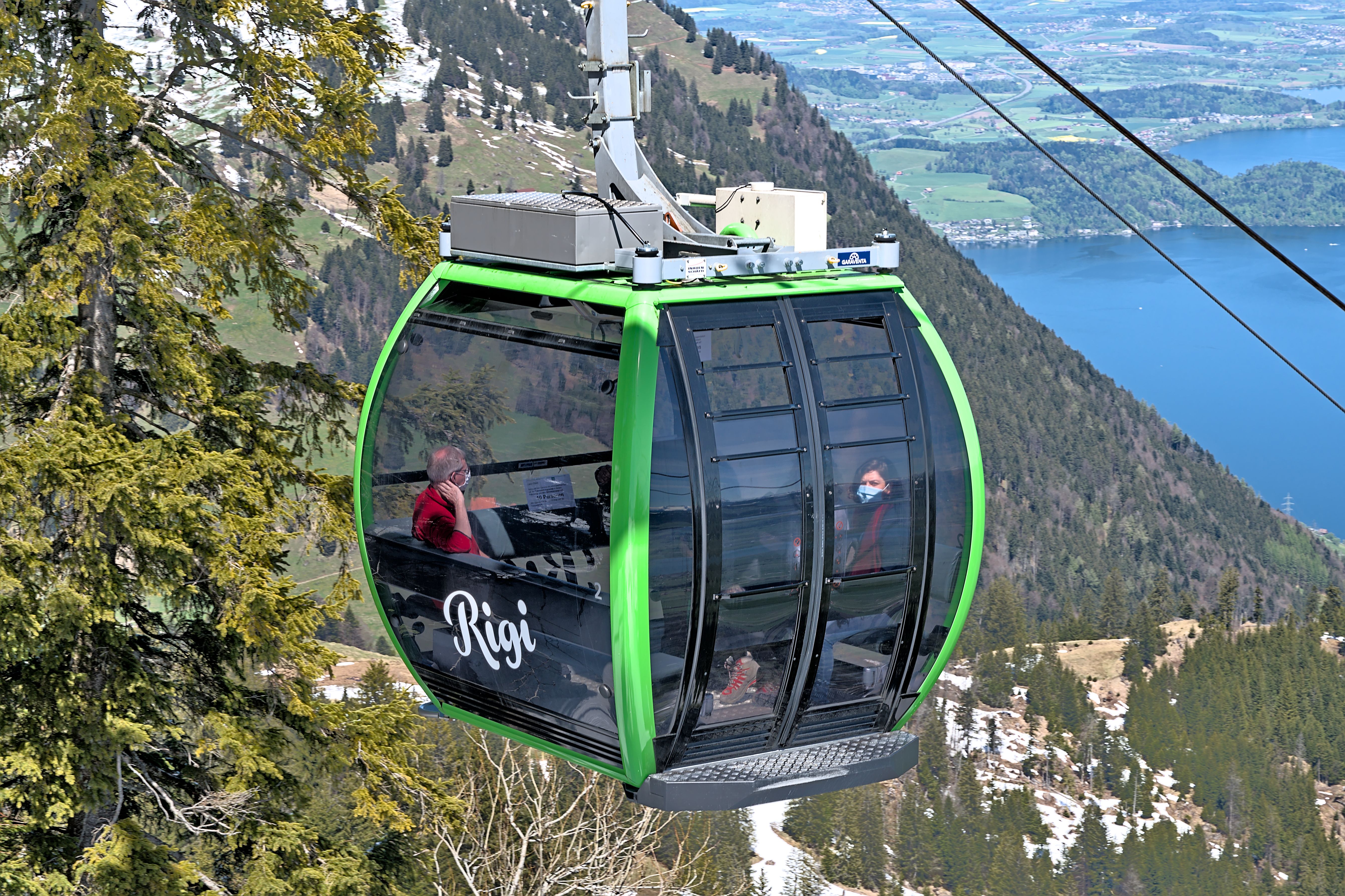 Interior of SkyOrb glass-floor cable car cabin showing harbour waters and greenery visible through the transparent floor
