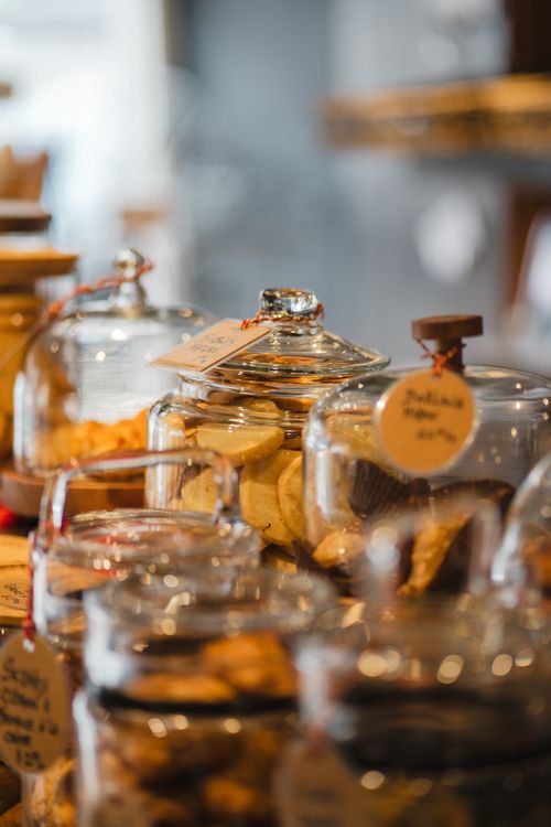 Free A variety of bakery items displayed in glass jars on a wooden counter inside a store. Stock Photo