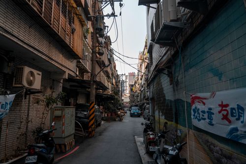 Free Explore a narrow urban street with buildings and signs in an Asian city, showcasing a unique cultural atmosphere. Stock Photo