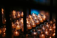 点燃的蜡烛静静排列，照亮了黑暗的房间，营造出宁静的氛围