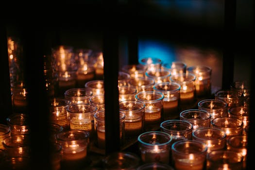 点燃的蜡烛静静排列，照亮了黑暗的房间，营造出宁静的氛围