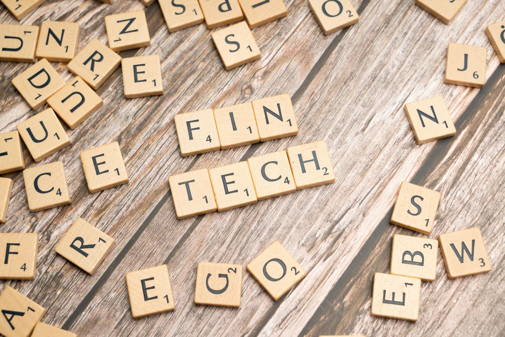 Fintech spelled out with wooden letter tiles on a rustic wooden background.