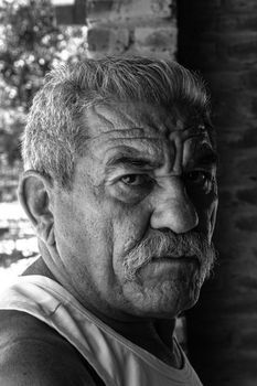 Black and white portrait of an elderly man with a mustache, highlighting his serious expression. - Fotografer Sidoarjo