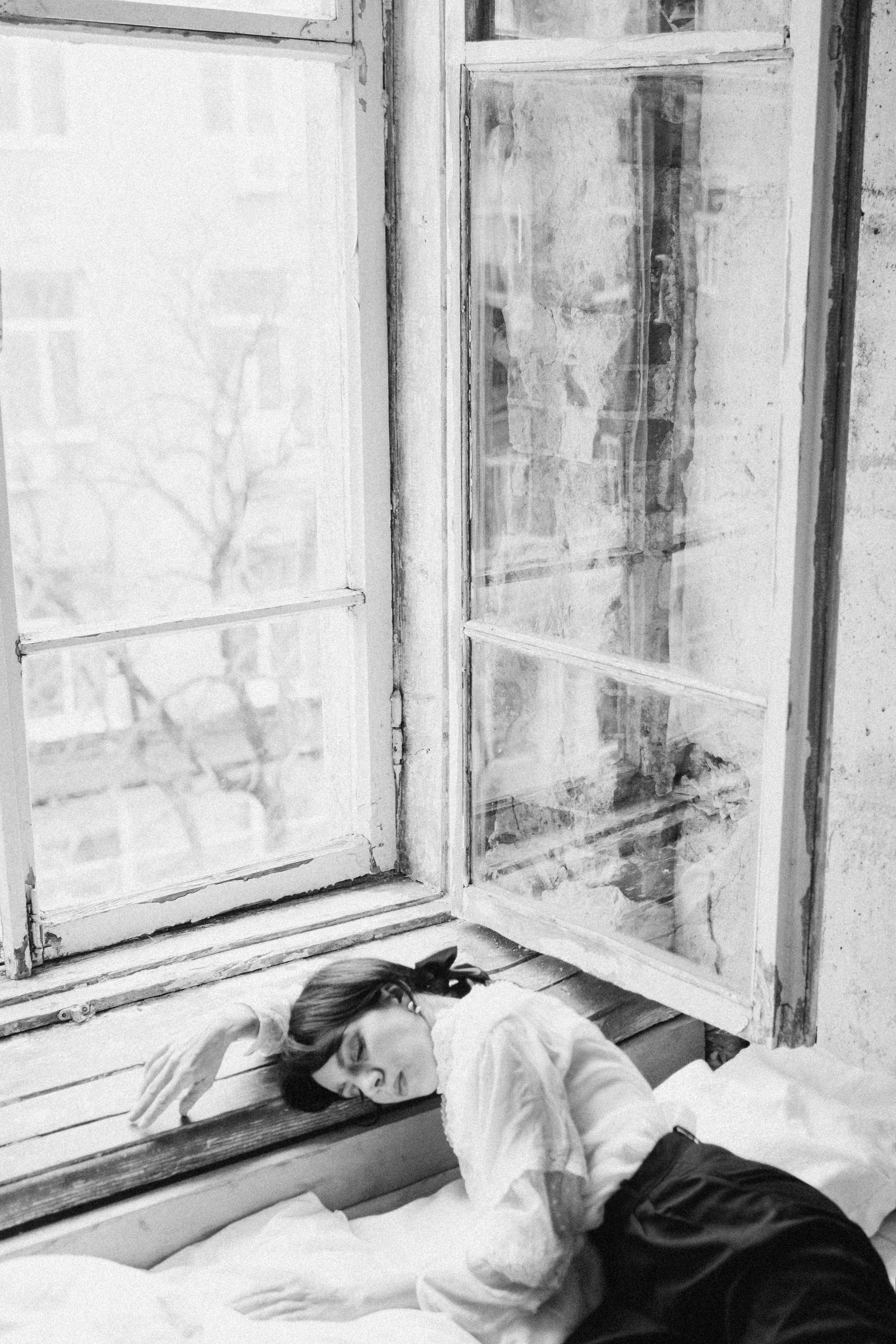 A woman rests on a windowsill, captured in monochrome artistry